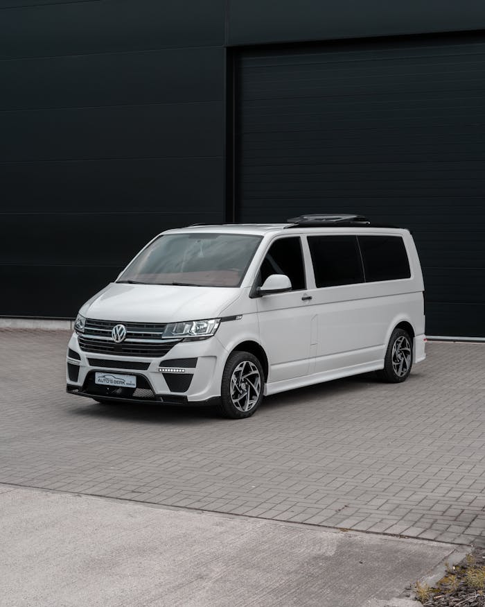 Sleek white Volkswagen van parked outside an industrial building with a dark facade.